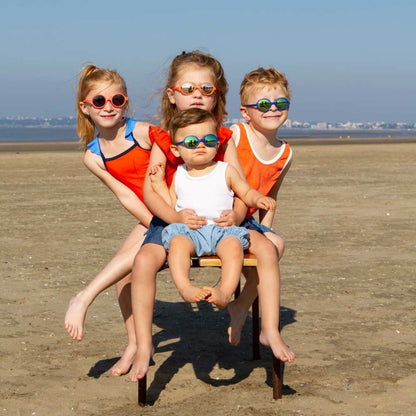 Lapsia rannalla aurinkolasit päässä.